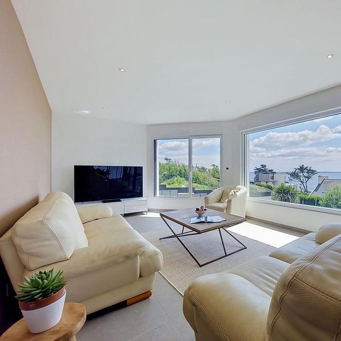 Salon lumineux avec canapés et baie vitrée sur la mer
