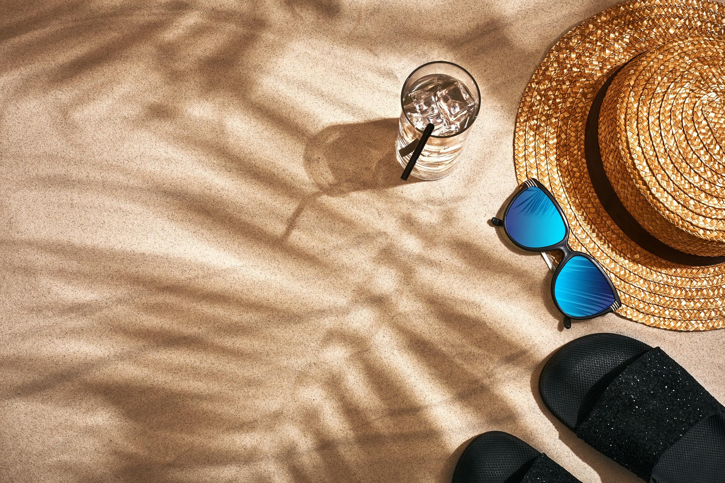 Strandhut und Sonnenbrille im Sand