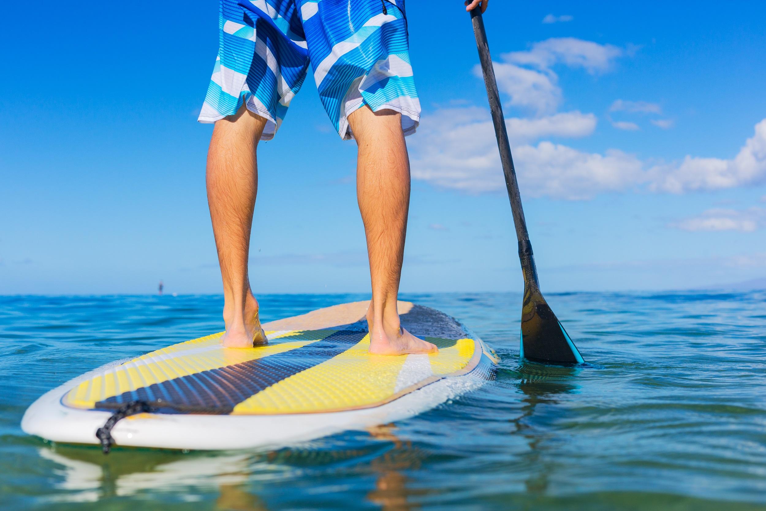 Man op stand-up paddleboard op het strand