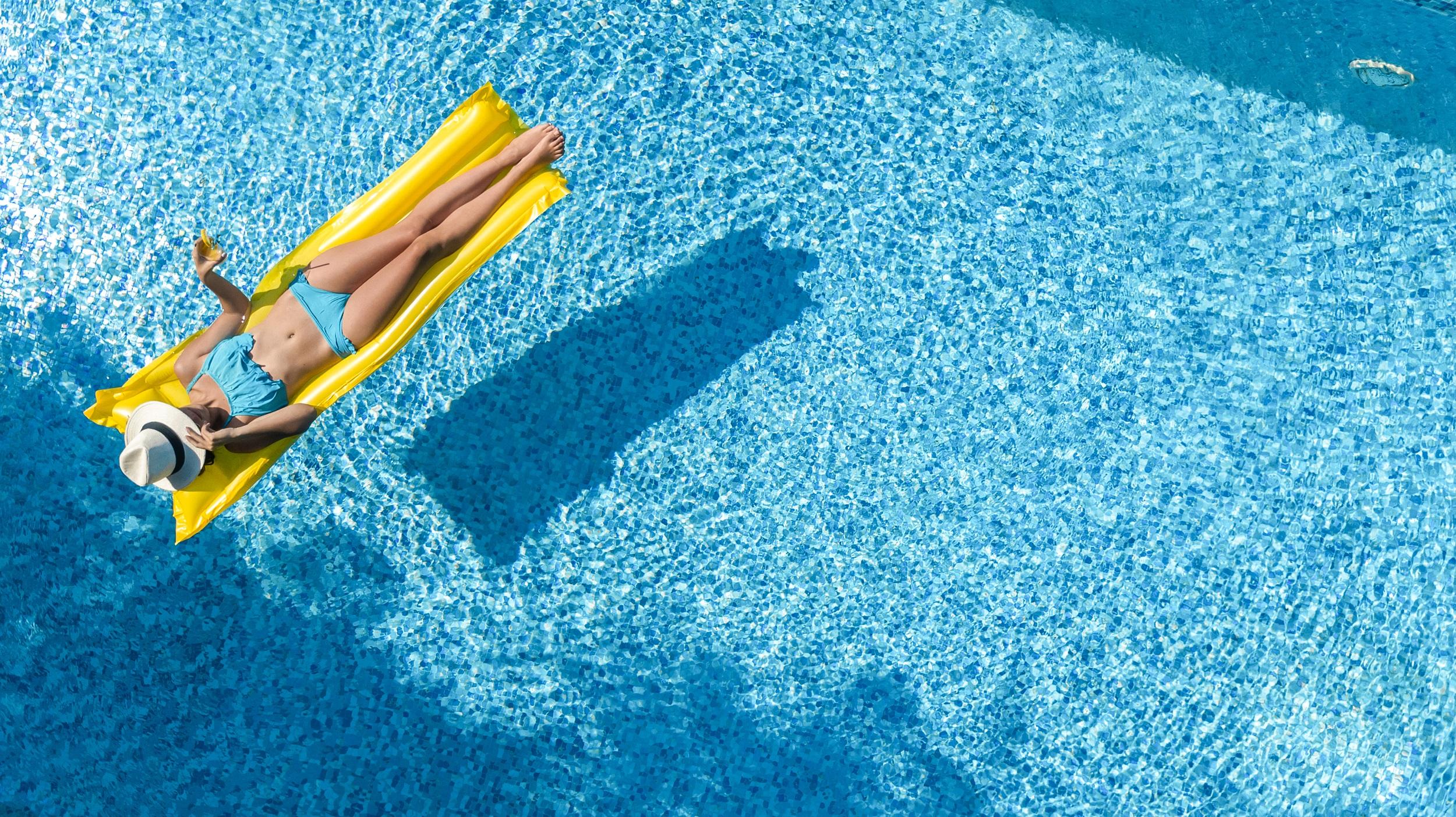 Mädchen im blauen Bikini auf einer gelben Matratze im Wasserpark
