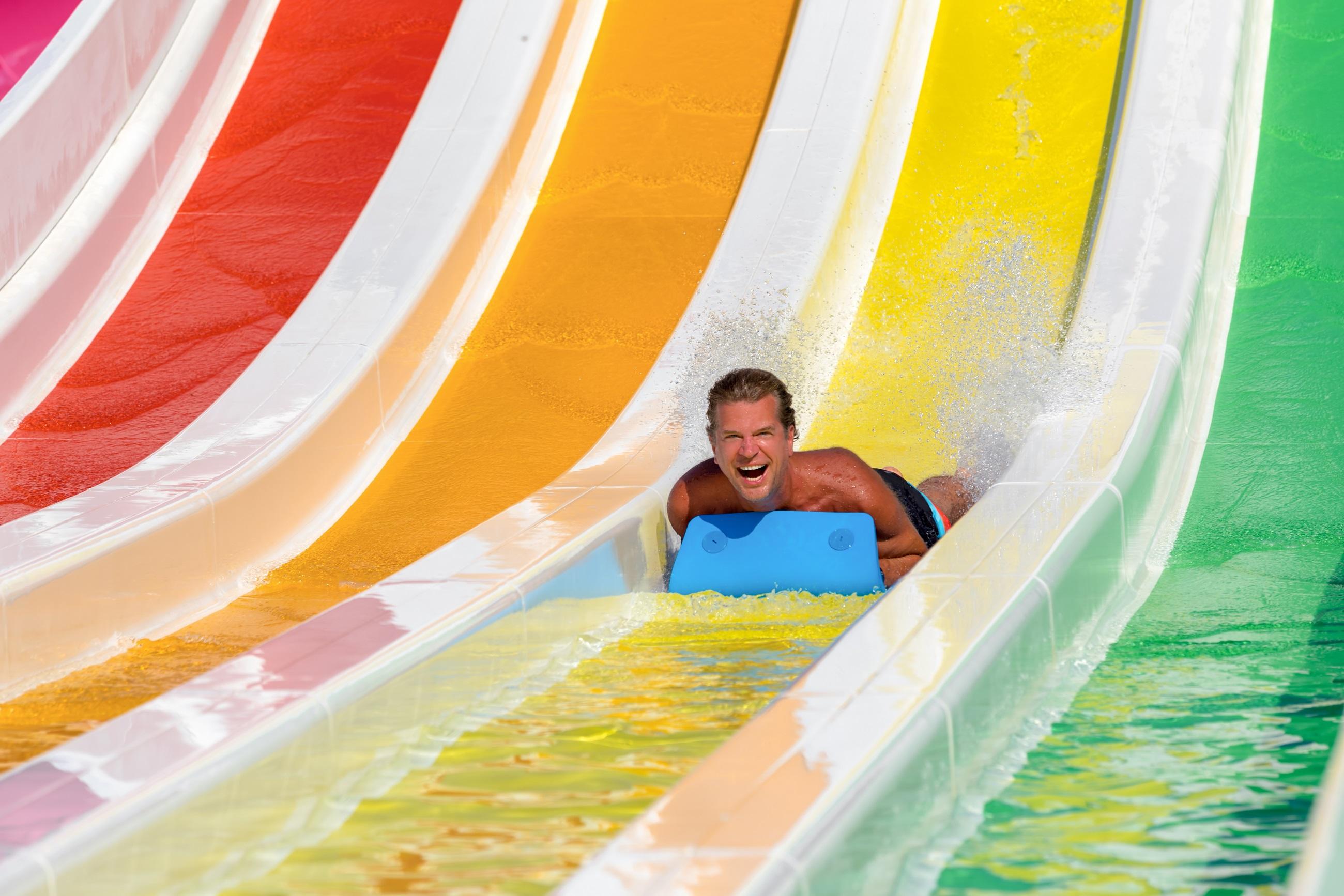 Man op een kleurrijke waterglijbaan in het waterpark