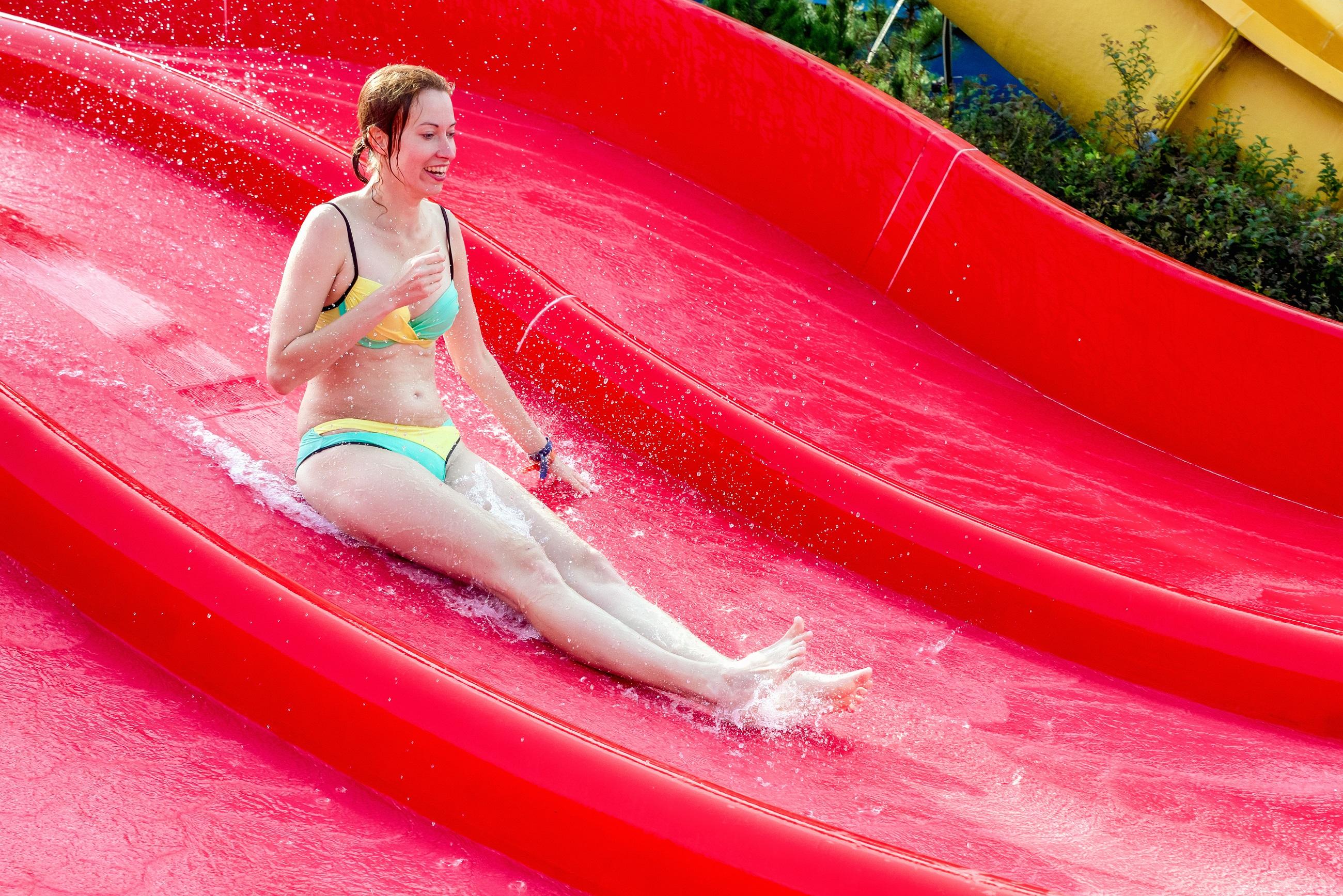 Frau im Bikini auf einer roten Wasserrutsche im Wasserpark